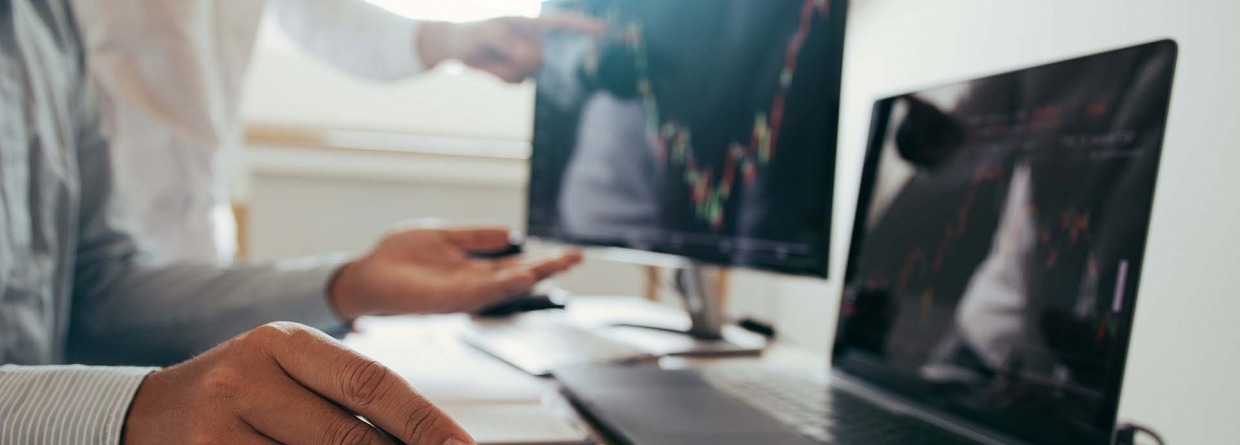 Risico analyse: close-up van 2 mannen welke data en grafieken aan het bekijken zijn op een laptop en beeldscherm