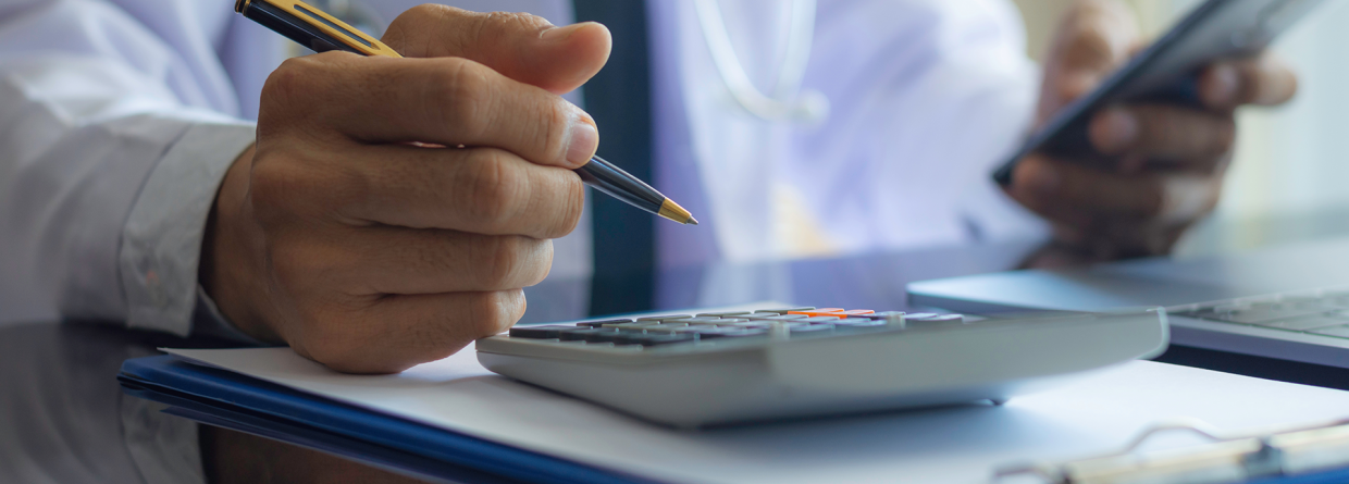 Eigenrisicodrager Ziektewet; man met een telefoon en een pen in zijn hand maakt berekeningen op zijn rekenmachine
