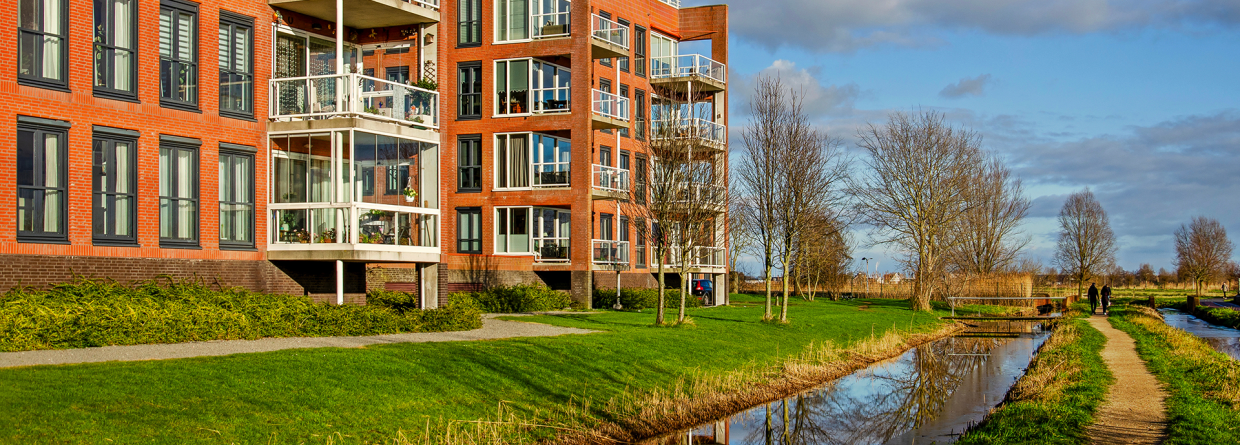 Appartementcomplexen in Pijnacker met gras voor de deur, een wandelpad en sloot